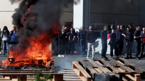 Reuters A wooden pallet burns outside the prison as guards watch on
