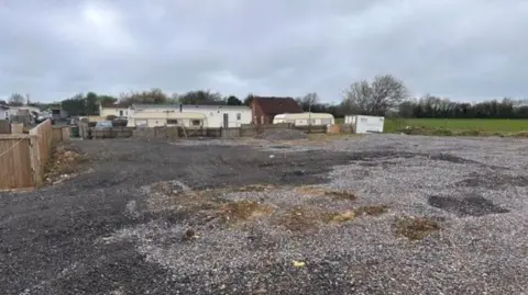 Somerset Council Image shows the Pine Residential site, with a large area covered in gravel and some caravans in the distance.