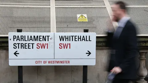 PA Media Civil servant walks past Whitehall sign