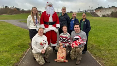 Handout The children's ward team and RAF students who accompanied Santa on the helicopter are standing outside with Father Christmas.