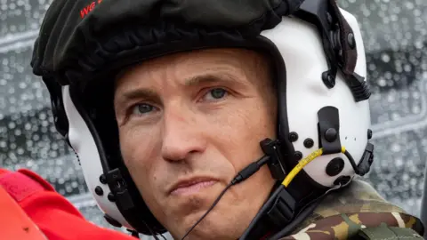 MOD A close-up image of a pilot's head, wearing a white helmet, he's got a stern look on his face, suggesting he means business.