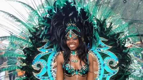 A woman wearing an extravagant blue and green peacock costume at St Paul's Carnival.