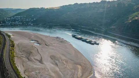 An aerial view as a cargo ship passes a huge exposed sandbar on the Rhine River