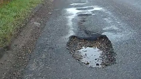 Badly potholed road.