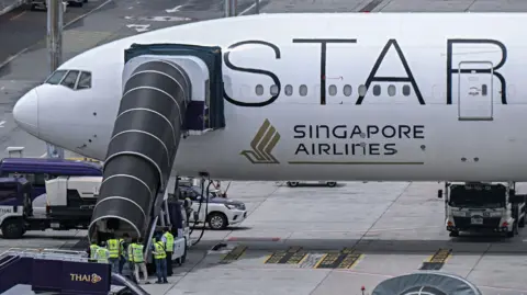 Getty Images Officials enter the Singapore Airlines plane after turbulence incident.