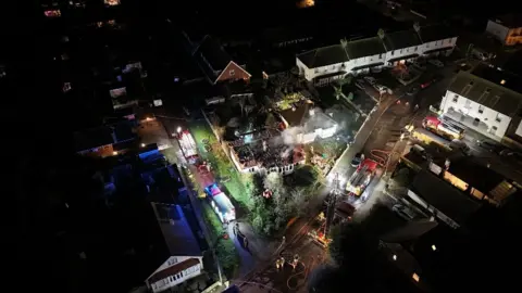 An aerial view of the house fire in Grand Drive with fire engines in the street and smoke coming from the burnt out house