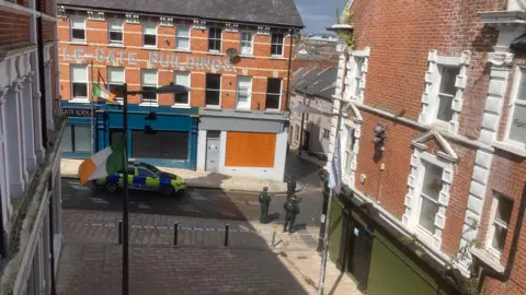 A view from a window of the scene where a police car is parked in front of a building