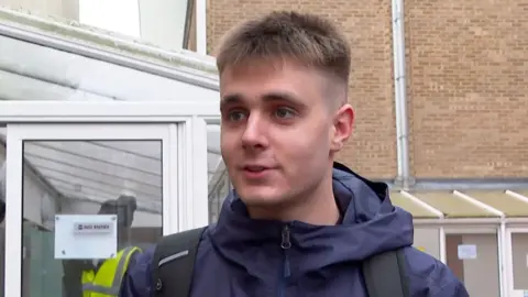 A young man with short hair wearing a blue jacket