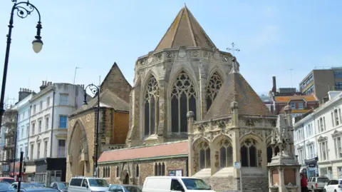 Street scene showing a church, parked cars, street lamp and buildings