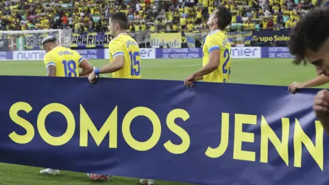 EPA Cadiz players with a sign saying "we are Jenni" ahead of their match against UD Almeria