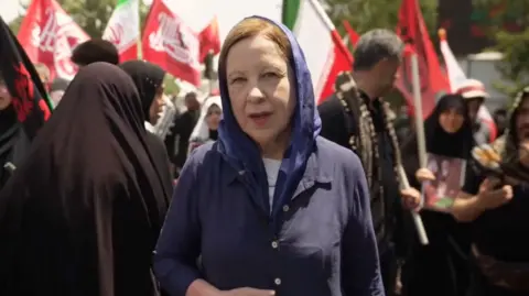 Lyse Doucet stands in the middle of a crowd in Iran