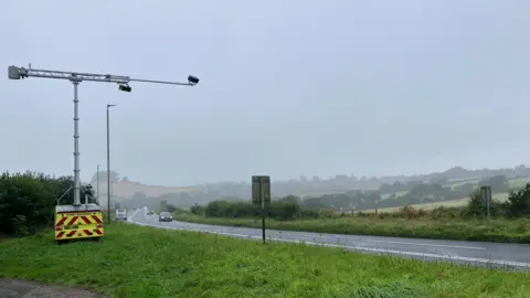 A trailer mounted with AI cameras on the left of the shot, with the A38 on the right side with vehicles on the road