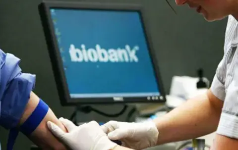 Nurse taking blood from person as biobank logo appears on screen in background.