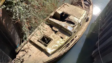 One of the boats which had sank into the River Avon. It has been brought to the surface and looks battered and broken.