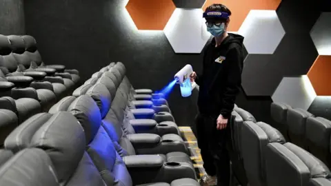 Getty Images An employee sprays disinfectant to seats at a cinema during its reopening on February 18, 2021 in Hong Kong, China.