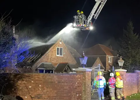 Firefighters putting out a house fire using an aerial ladder