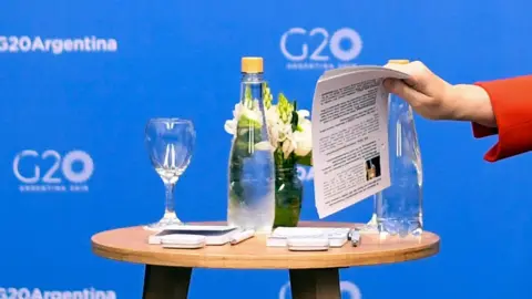 EPA Angela Merkel takes a briefing note about Scott Morrison during their G20 meeting