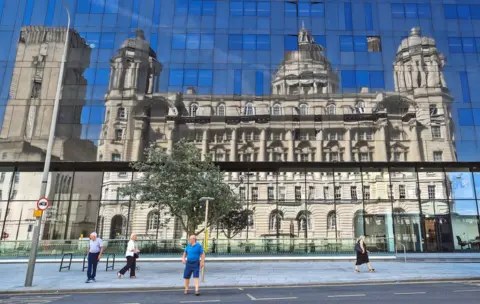 PA A reflection of the Port of Liverpool Building under blue skies seen in a glass building