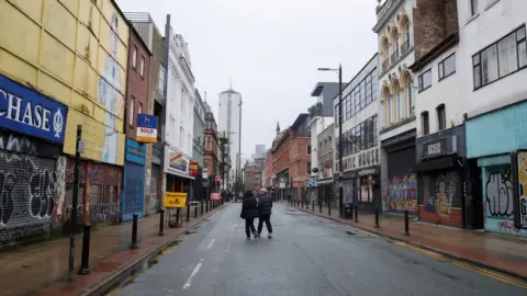 Reuters People walking down an empty street in Manchester