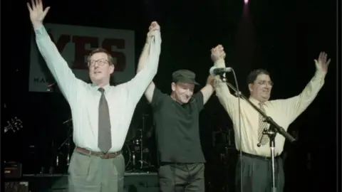 Press Association Ulster Unionist leader David Trimble (left), U2 singer Bono, and SDLP leader John Hume on stage for the YES concert at the Waterfront Hall in Belfast in 1998