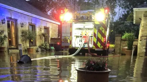Cambridgeshire Fire and Rescue Fire engine pumping water from flooded garden
