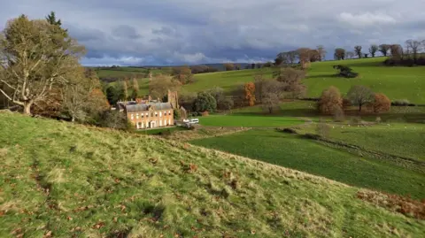 Field Studies Council The image shows Nettlecombe Court, a grand house, nestled between green fields and trees. 