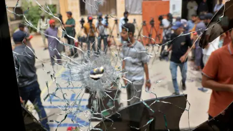 Reuters Men in plain clothes and some in police uniform are seen through a broken glass window with a hole created by some sort of impact.