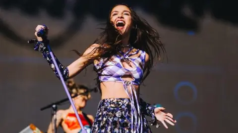 Olivia Rodrigo posa con su soporte de micrófono, mientras juega en el Festival de Glastonbury en 2022