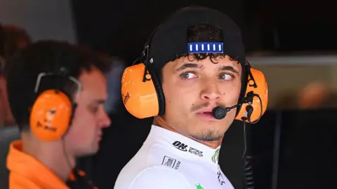 Lando Norris wears headphones in the McLaren garage 