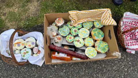 Baskets full of iced Easter cakes, painted eggs and sausage.