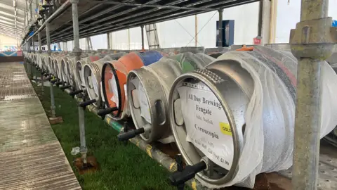 Tom Jackson /BBC Barrels of beer stacked in rows at the venue 