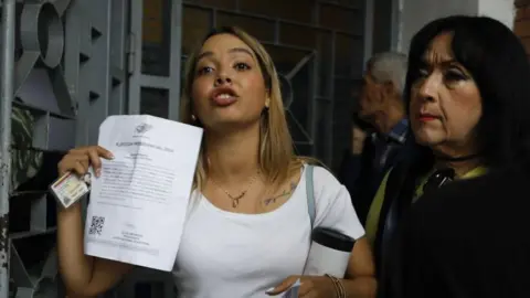 Getty Some voters react as they have to wait in line as access for opposition election observers is delayed at the Andres Bello School, before the opening of polls for the presidential elections in Caracas, Venezuela on July 28, 2024.