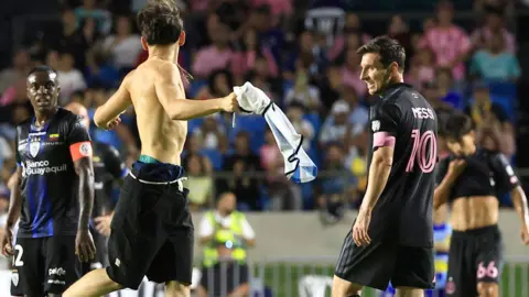 Lionel Messi being approached by the pitch invader who tackled him to the ground