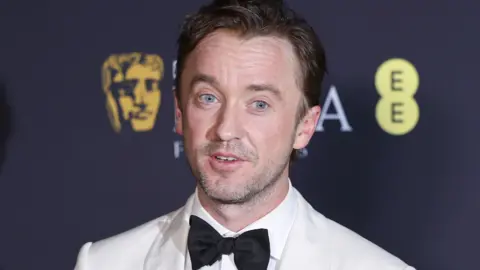 EPA Tom Felton in a white suit and black dickie bow at the recent Bafta Awards