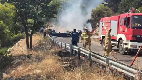 Firefighters and forensic experts work at the crash site after two firefighting helicopters collided mid-air west of Athens. Photo: 2 August 2026