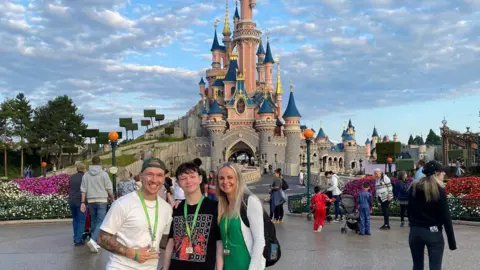 Lauren Johansen Jay with his mum Kate and taxi driver Tom in front of the Disneyland Paris castle