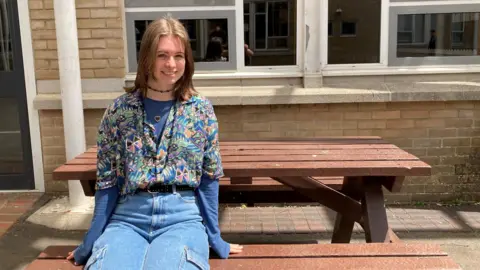 John Cabot student Jess sat on a picnic bench