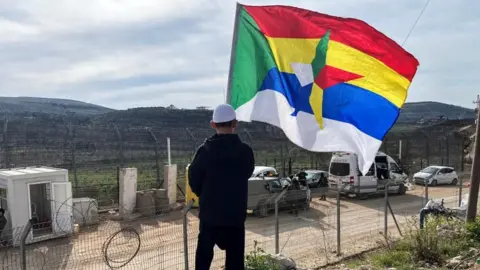 Boy holds a large Druze flag as he looks out towards the ceasefire line between the Israel-occupied Golan Heights and Syria (file photo)