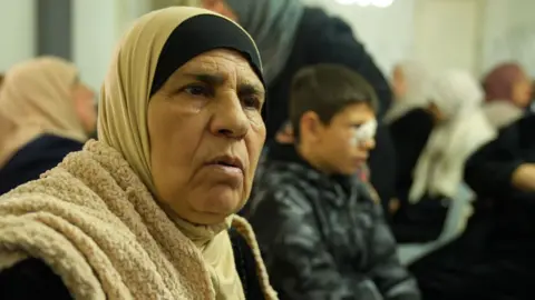 Najah Bani Odeh sits near her grandson Mustafa Bani Odeh, at a gathering for mourners at her home in Tammun, in the Israeli-occupied West Bank
