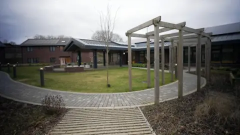 A view of the buildings inside the Lilias Centre, with a patch of grass and a path in the foreground. 