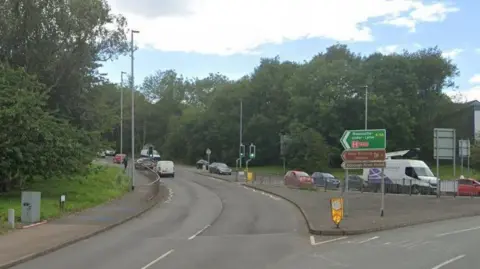 A Google street view image showing a road leading off a roundabout.