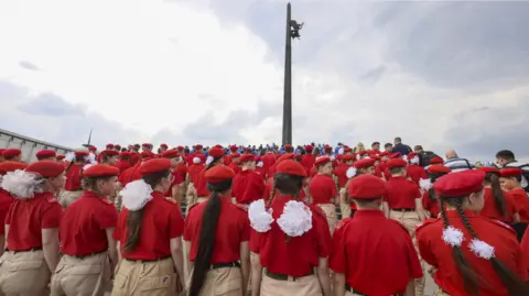 EPA A crowd of young children in Moscow, face away from the camera wearing the Yunarmia uniform: a red polo and beige khakis, as well a a red beret. The girls are wearing large white scrunchies.