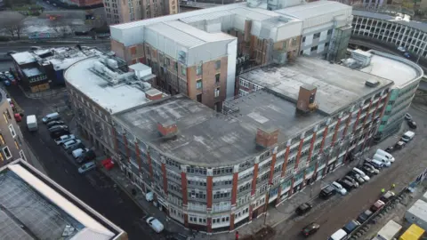 Newcastle Cathedral An aerial photo of Carliol Square where Newcastle Prison used to stand which is covered by a large building with curved corners and six storeys. There is a modern block of apartments behind the building and parked cars surrounding it.