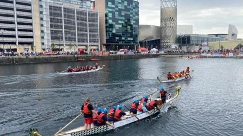 teams of dragon boat racers compete in Salford Quays