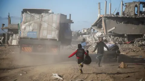 Reuters Palestinians run towards an aid lorry in Rafah, southern Gaza (20 January 2025)