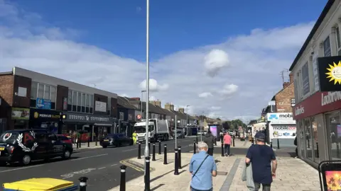 Joe Griffin/LDRS Shoppers walking on a pavement in Lincoln Road in Peterborough. There are shops on either side of the road.