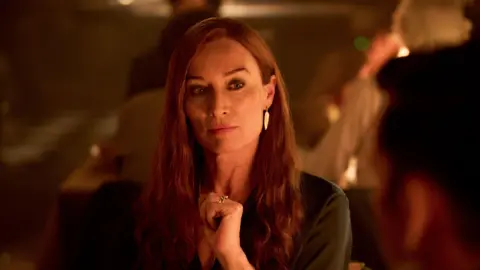 Robert Viglasky/Disney+ Victoria Smurfit as Maud O'Hara. She has long red hair and wearing dark clothing, earrings and a ring.