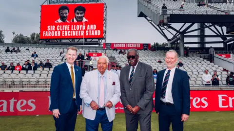 Lancashire County Cricket Club The pair pictured with club staff earlier as the stand was unveiled, both wearing suits, with the name of the stand revealed on a big screen in the background