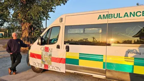 Rotary Club of Northampton Becket David Smith with short white hair standing next to ambulance with Great Doddington banner