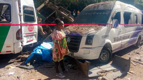 A woman stands next to vehicles destroyed by a bomb attack at El Tunel, on the Popayan-Cali road, in Cajibio, Cauca department, Colombia.
